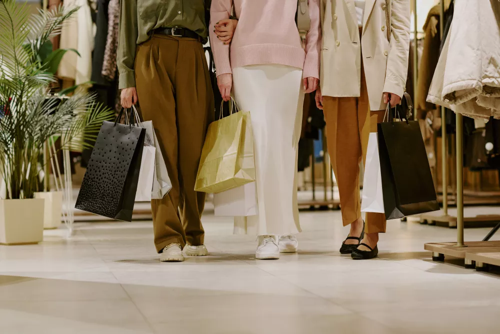 Three people walking through a clothing store with shopping bags.